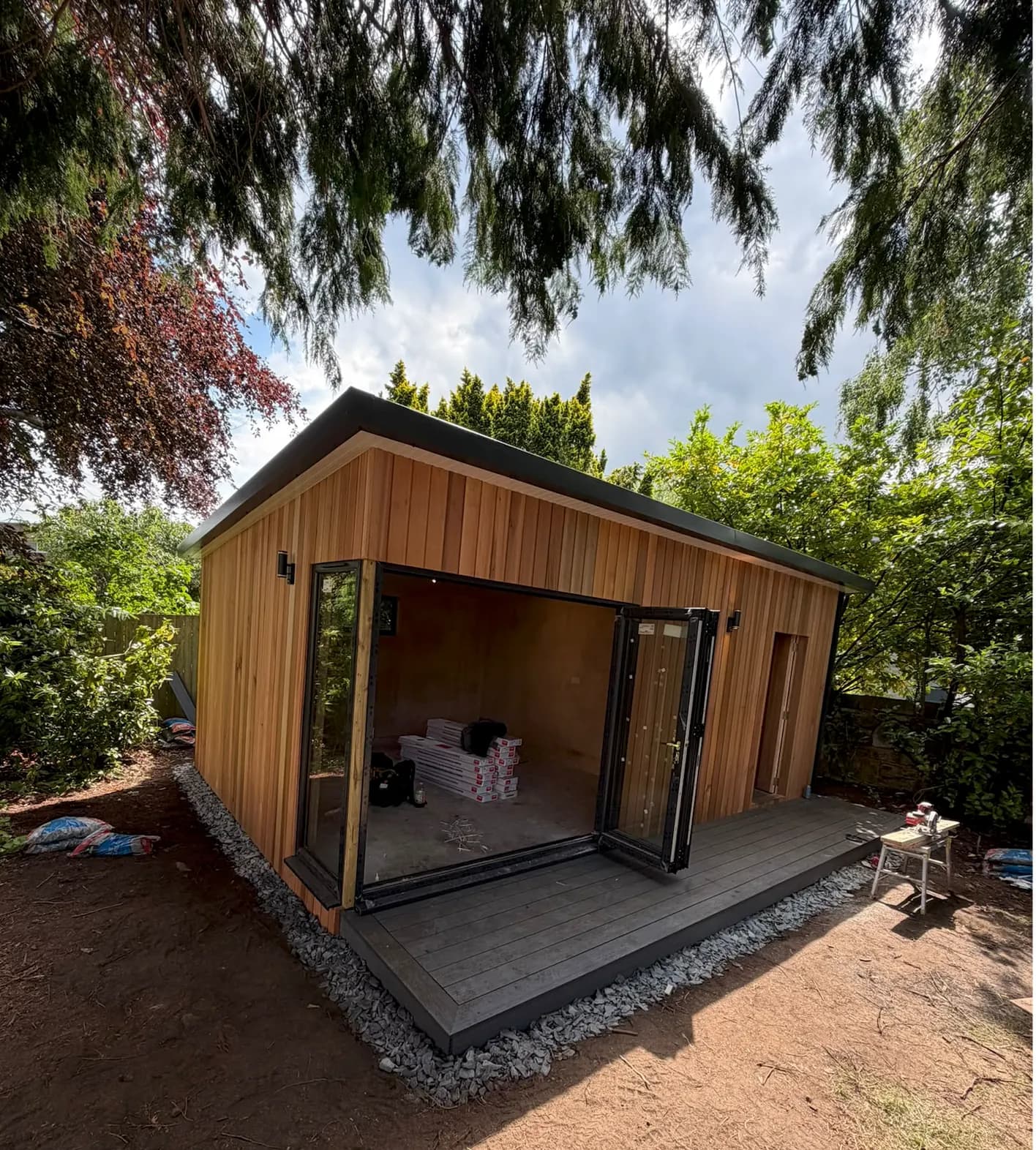 Timber-clad garden room with exterior wall lights and open folding doors